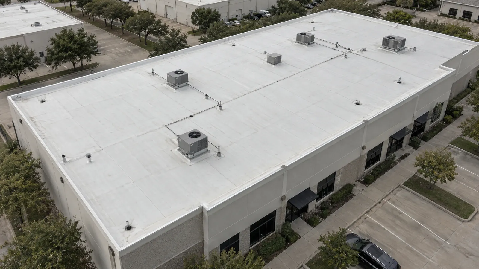 Aerial view of a flat commercial roof with a white membrane and rooftop HVAC units